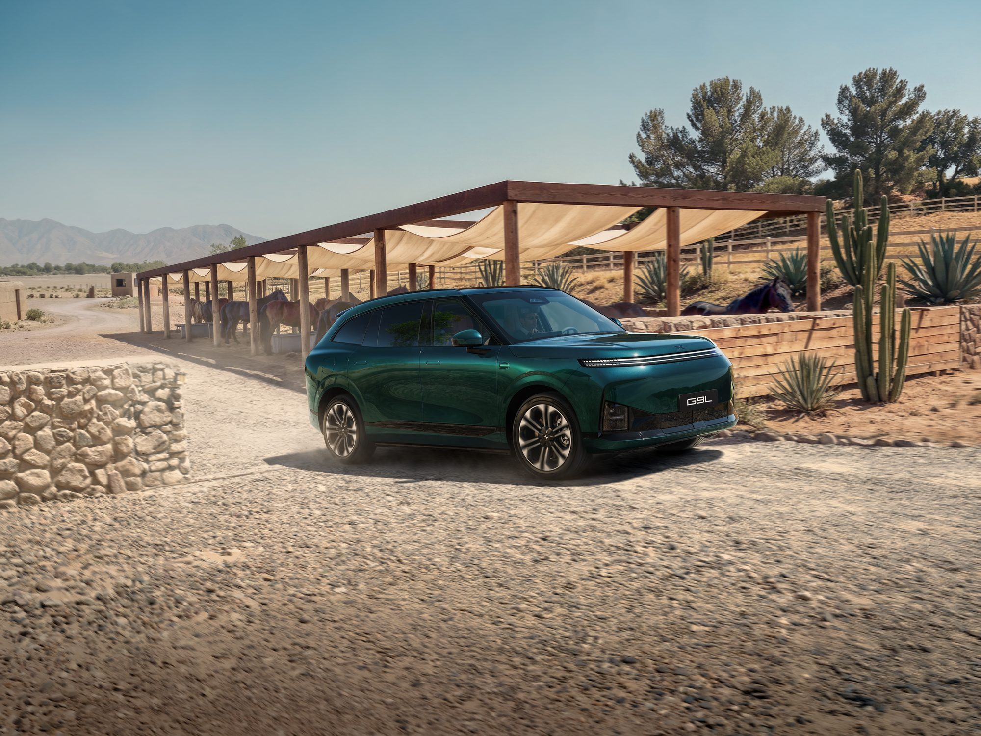The XPENG G9L in green driving on a gravel track past a ranch