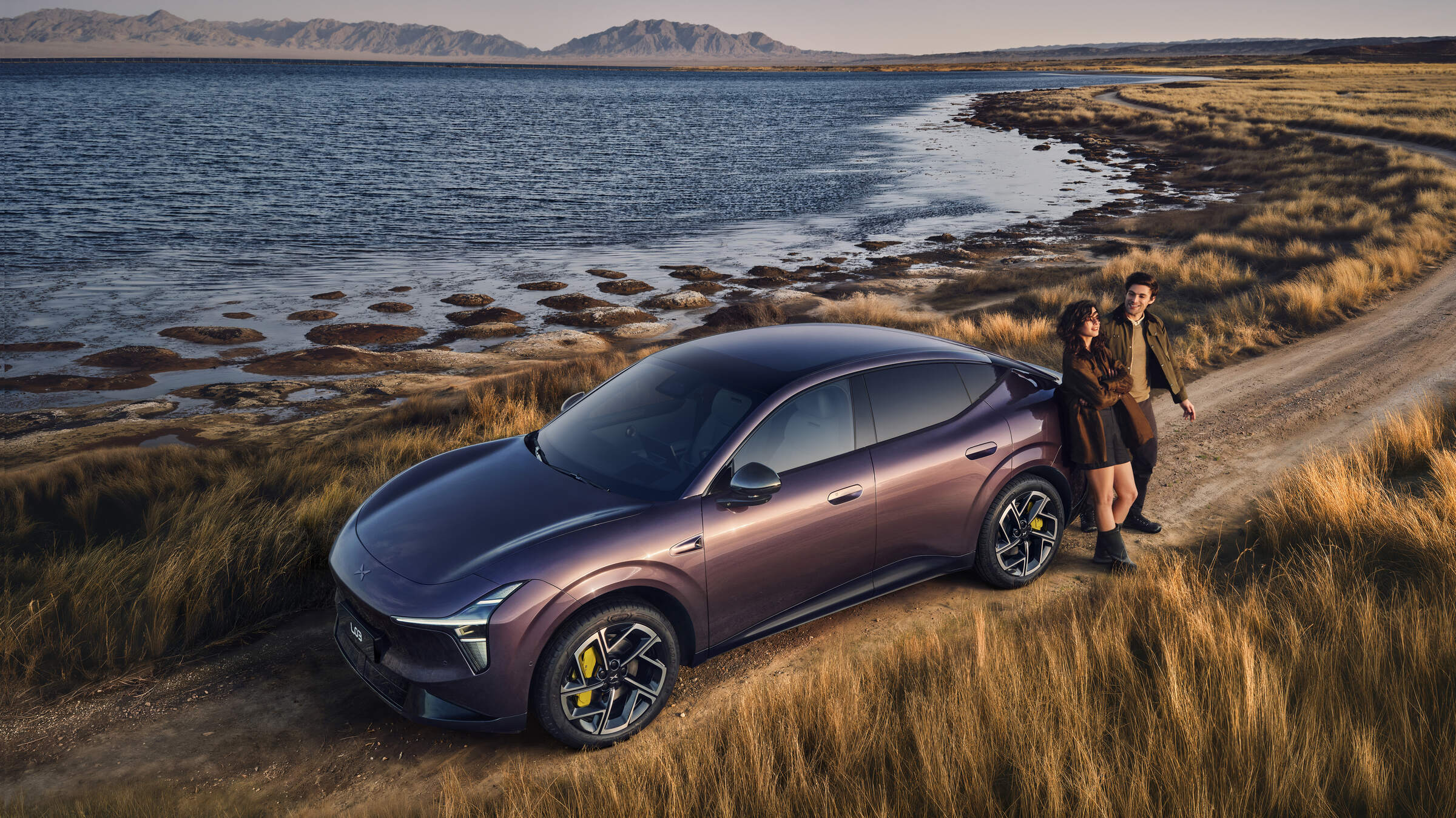 The XPENG L03 REEV in plum on a dirt track by a lake